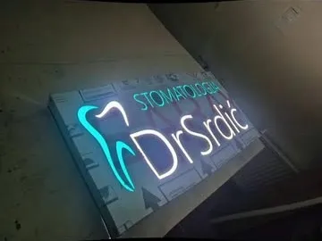 Svjetleći logo sa zubom i natpisom DrSrdić na tabli stomatološke ordinacije