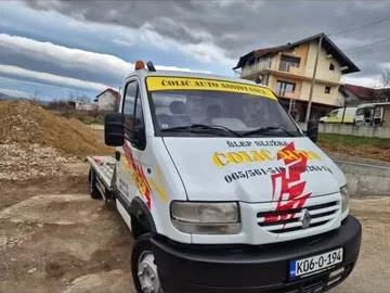 Bijelo šlep vozilo sa crveno-žutim grafikama i natpisom šlep službe na haubi